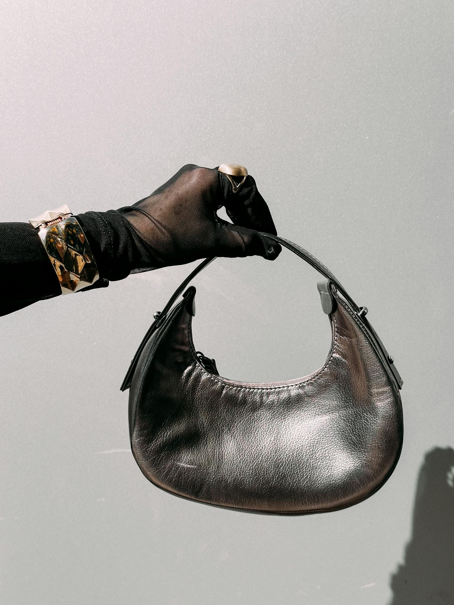 Close-up of a gloved hand holding a silver leather purse, showcasing elegant fashion accessories.