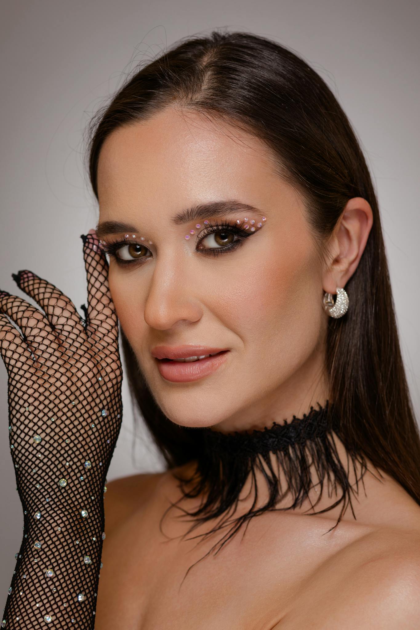 Close-up portrait of a stylish woman with glamorous makeup, wearing a fishnet glove and black choker.